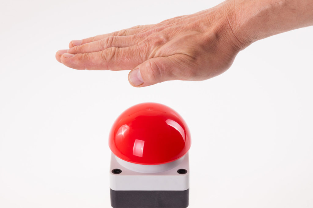 Hand pushing a red buzzer